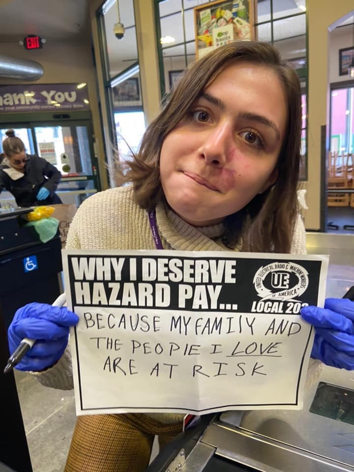 Women holding a sign saying "Why I Deserve Hazard Pay... Because my family and the people I love are at risk"