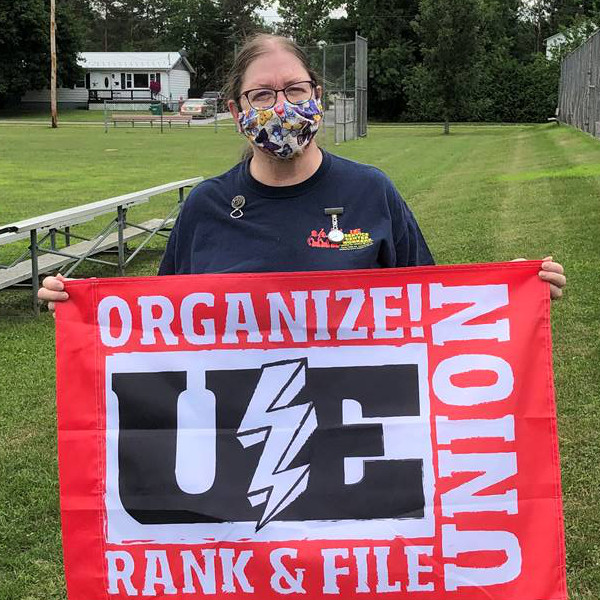 UE member in a mask with a red UE flag with the words "Organize! Rank & File Union"