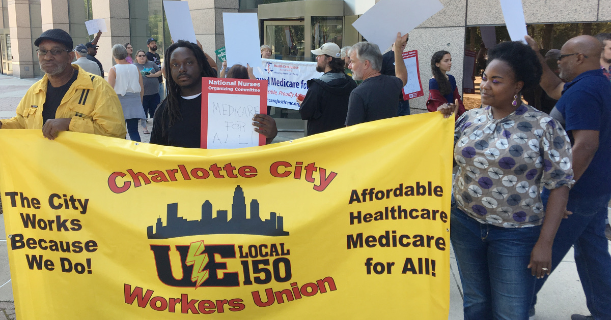 Two UE members holding a sign reading "Charlotte City Workers Union, UE Local 150. The City Workers Because We Do! Affordable Healthcare Medicare for All!"