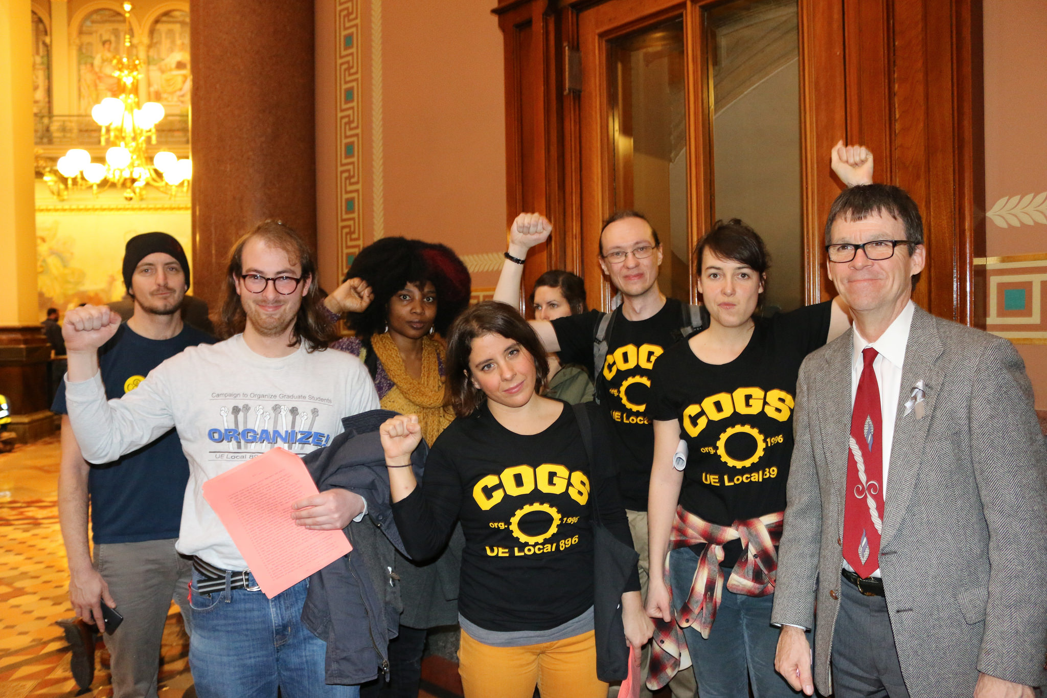 UE Local 896-COGS members in the Iowa state capitol building, with raised fists