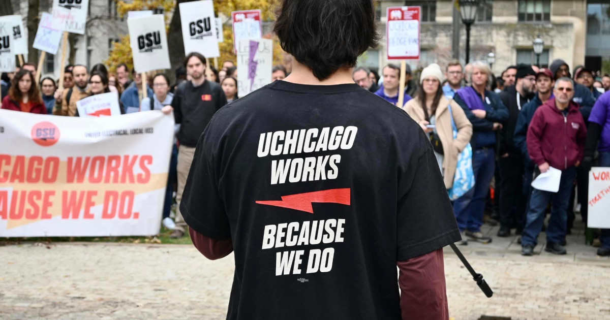 Back of a grad worker wearing a t-shirt reading UChicago Works Because We Do in front of a rally of GSU members