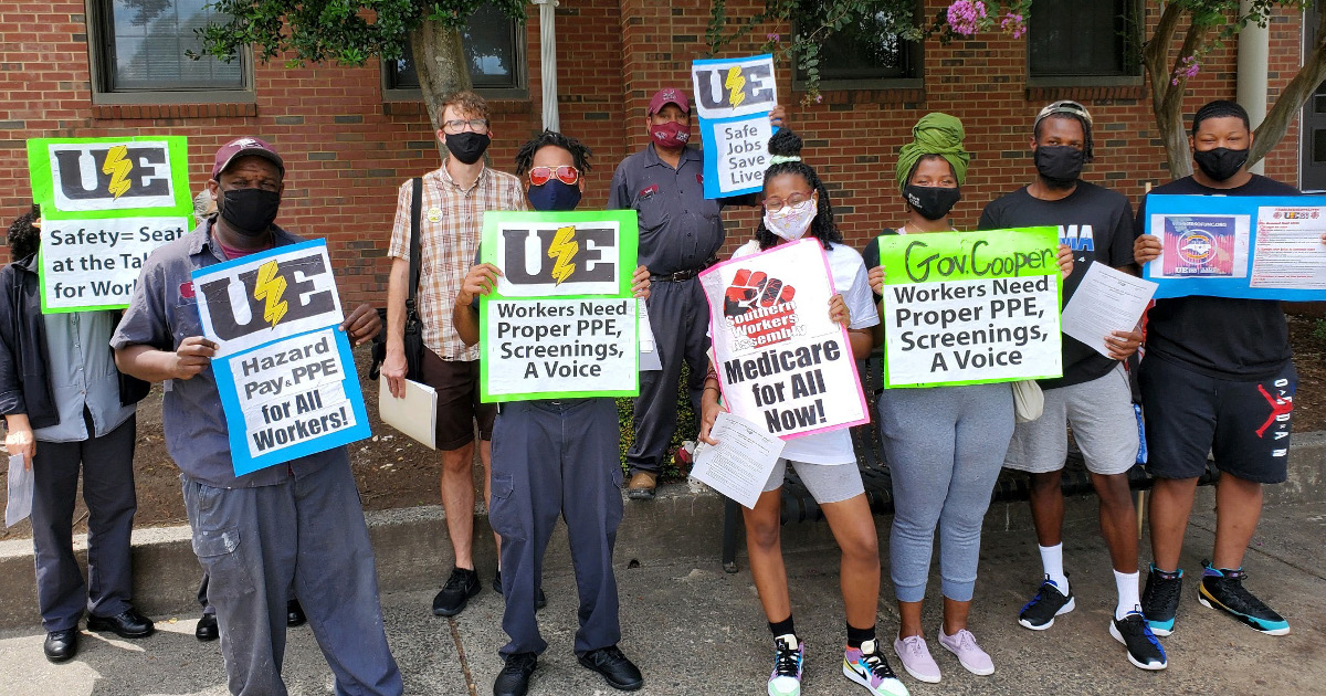 Workers holding UE signs demanding hazard pay, PPE, screenings and a seat at the table