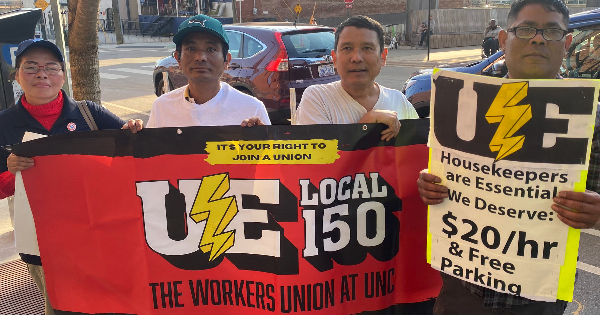 Workers with a union banner and a sign reading Housekeepers Are Essential We Deserve $20/hour and Free Parking