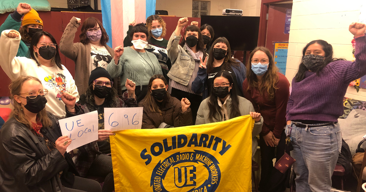 UE Local 696 members with raised fists and a UE Solidarity Forever banner