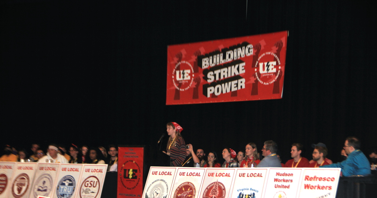 A graduate worker speaking on a stage full of other graduate workers