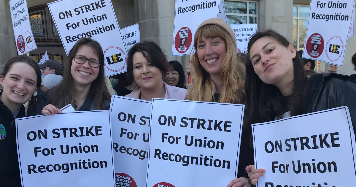 Five graduate workers with signs reading On Strike for Union Recognition