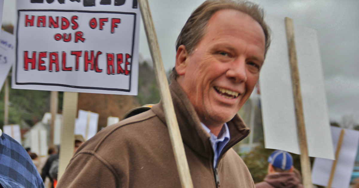 Photo of UE President Peter Knowlton with a picket sign that says "Hands off our healthcare"