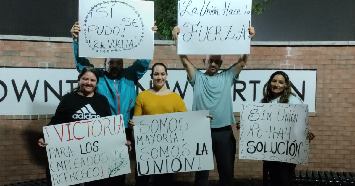 Workers holding up signs in Spanish
