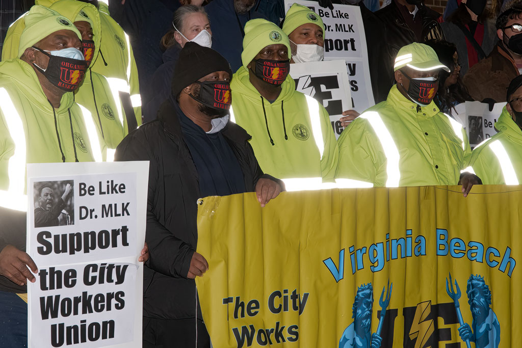 City workers wearing reflective gear and UE masks. Worker on the left holds a sign reading Be Like Dr. MLK: Support the City Workers Union