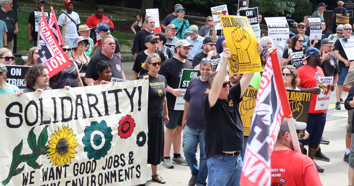 Workers and supporters rally outside Wabtec corporate headquarters with signs and banners