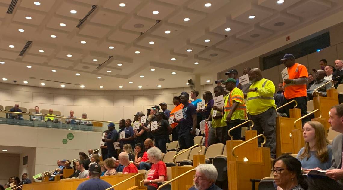 UE Local 150/Charlotte City Workers Union members holding signs at the Charlotte City Council meeting