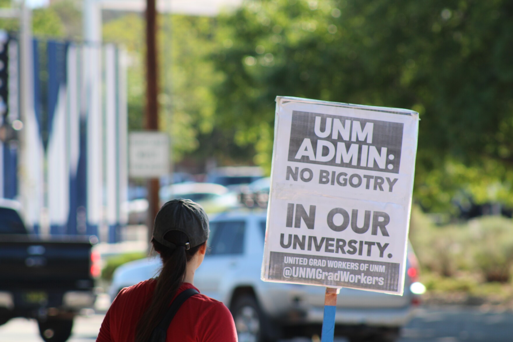 Grad worker holding up picket sign reading UNM Admin: No bigotry in our university.