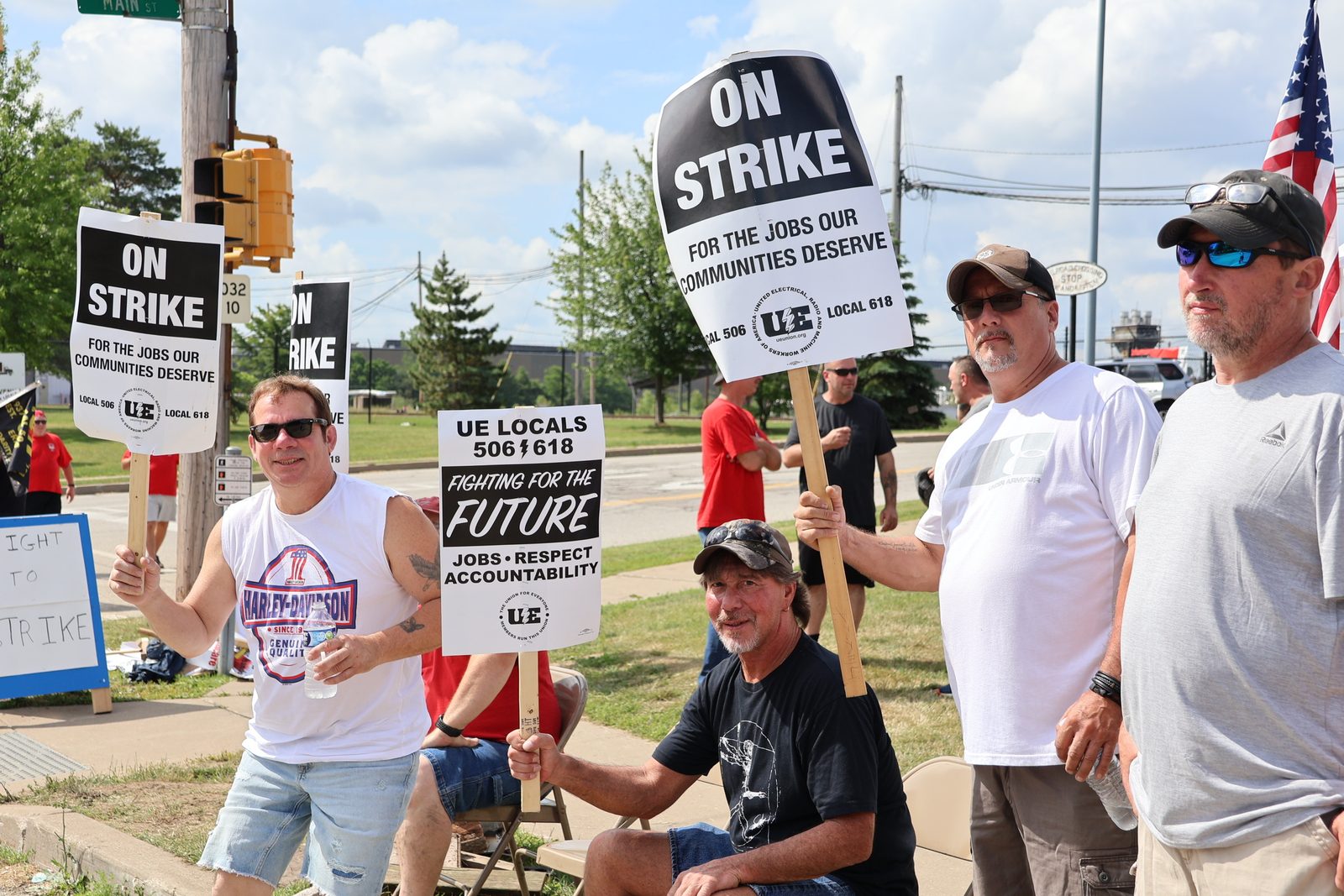 UE Local 506 members picketing in the sun; one worker holds a water bottle.