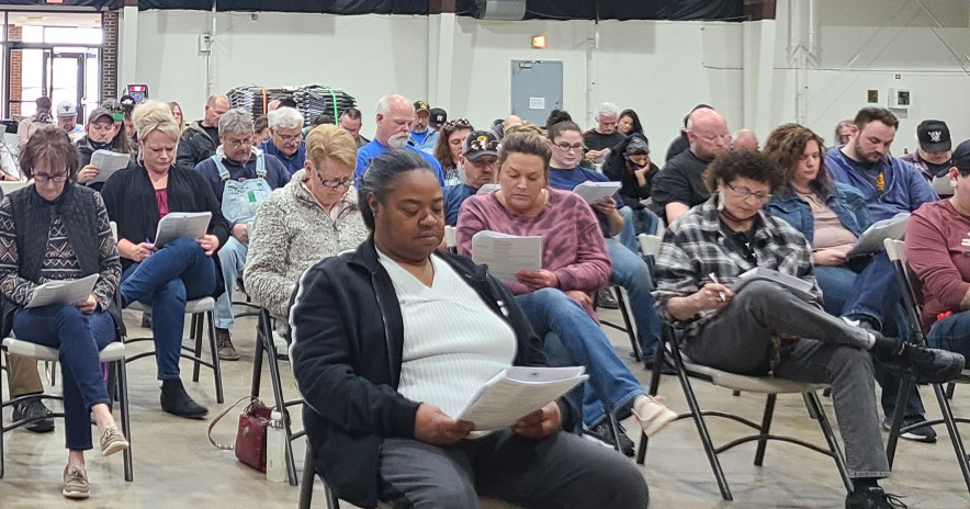 Workers sitting in folding chairs reading contract summaries