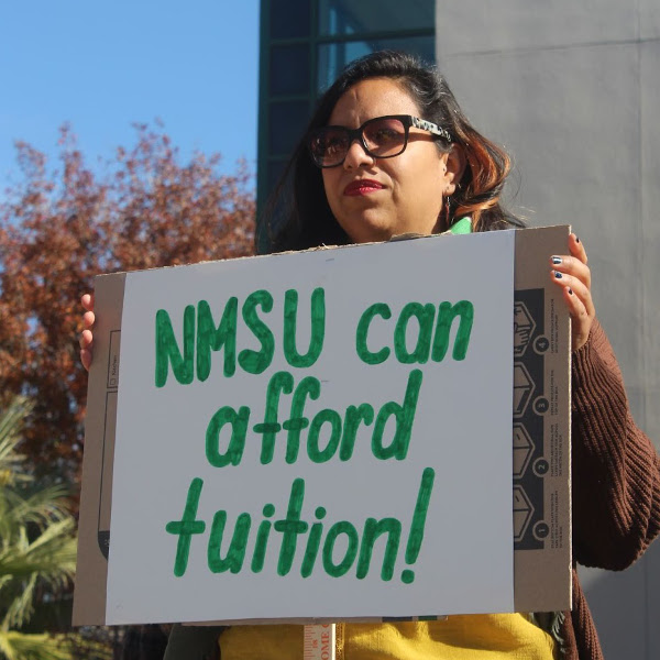 Grad worker with a sign reading NMSU Can Afford Tuition