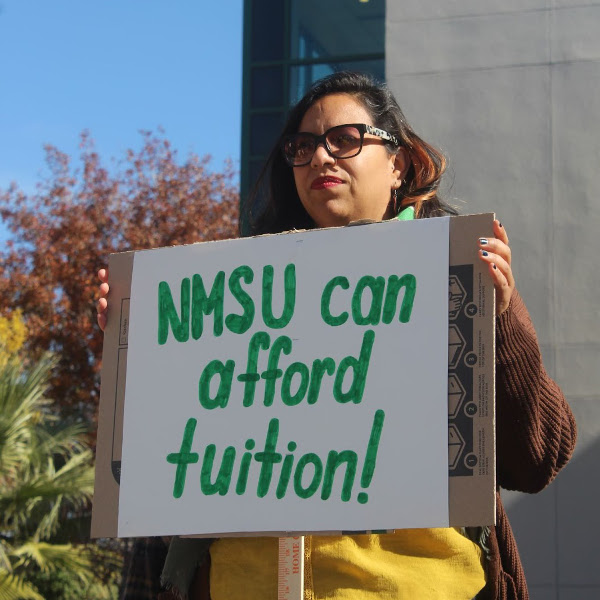Graduate worker with sign reading NMSU can afford tuition!