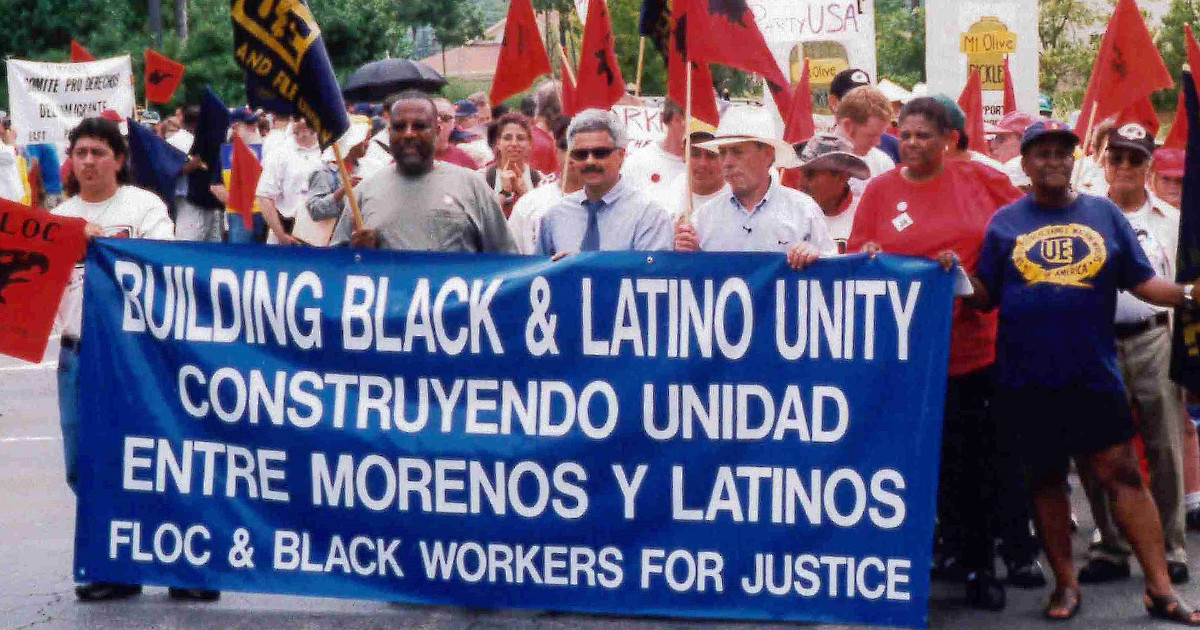 Workers marching behind a banner that reads Building Black and Latino Unity / FLOC and Black Workers for Justice