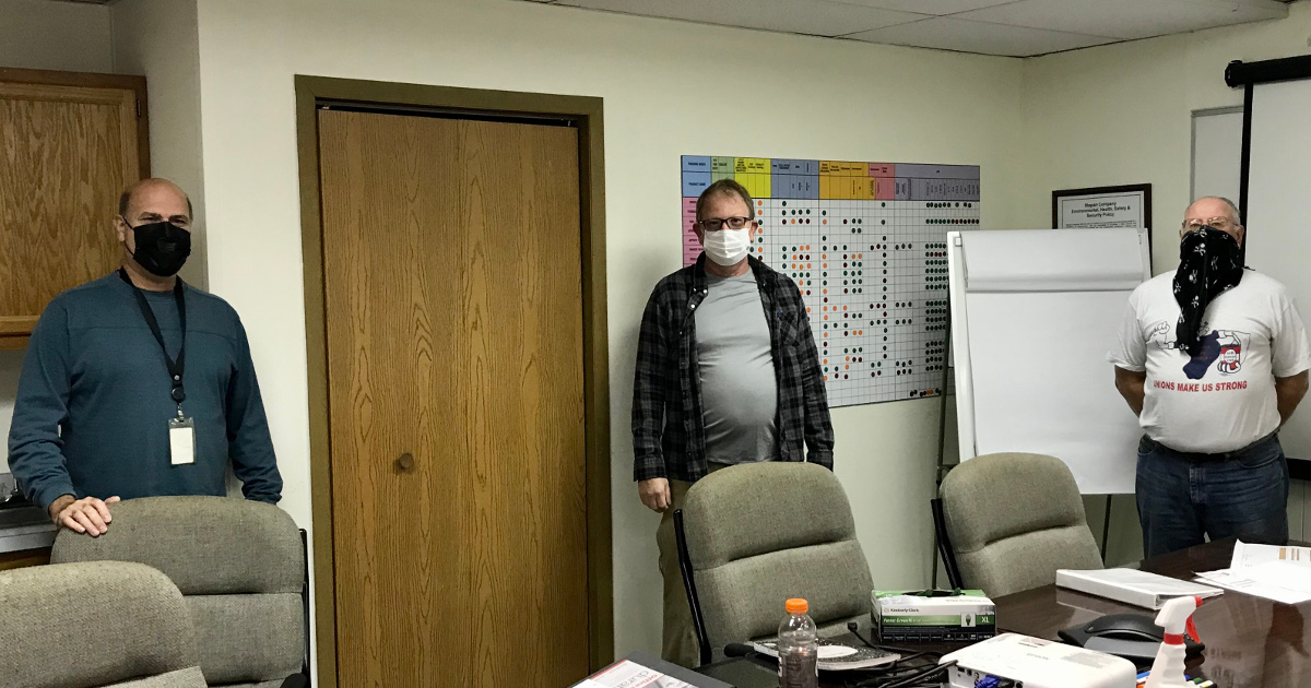 Three union bargaining committee members wearing masks and socially distancing