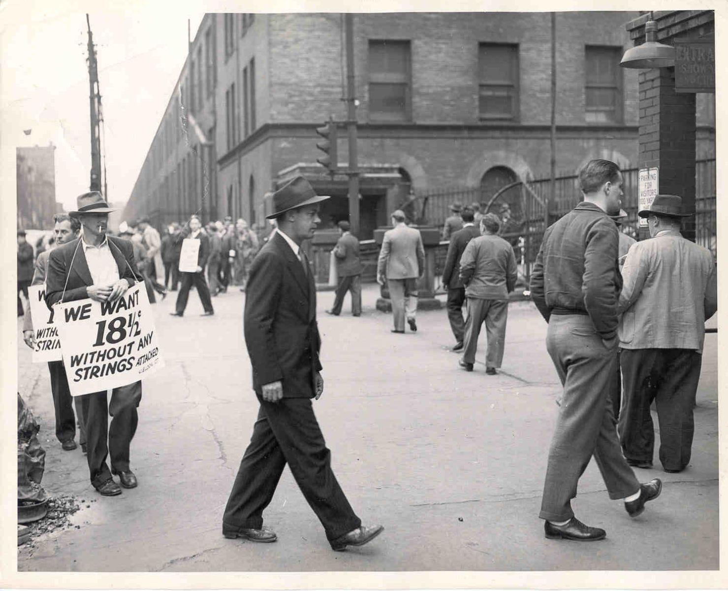 Men walking in a picket line outside a factory