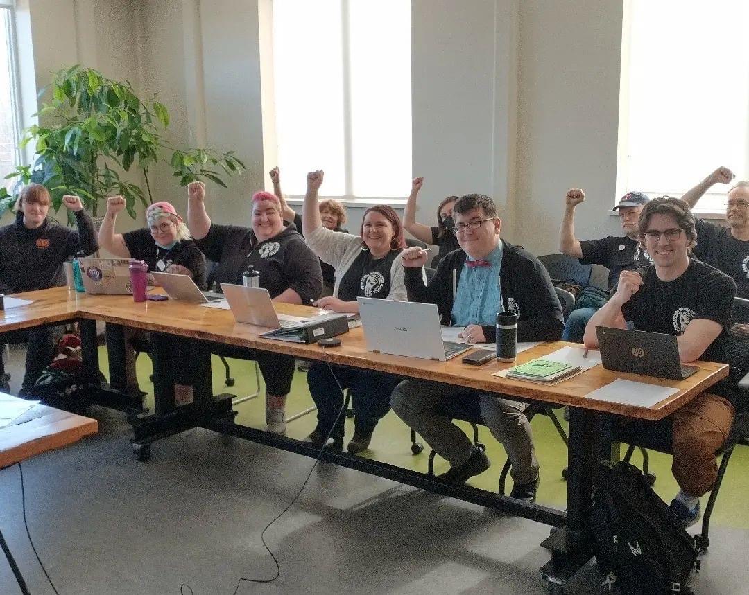 UE Local 203 negotiating committee and members in a conference room with raised fists