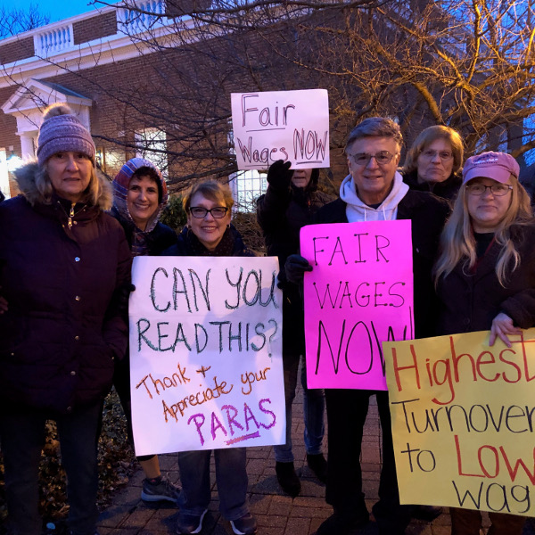 Paraprofessionals holding signs demanding fair wages now