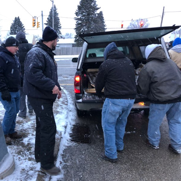 Photo of men unloading wood from the back of a truck