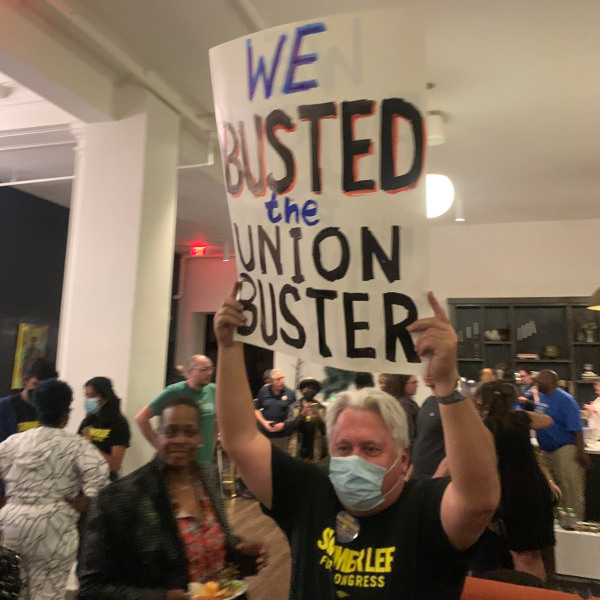 Man wearing a Summer Lee for Congress t-shirt holding up a sign reading We Busted the Union Buster