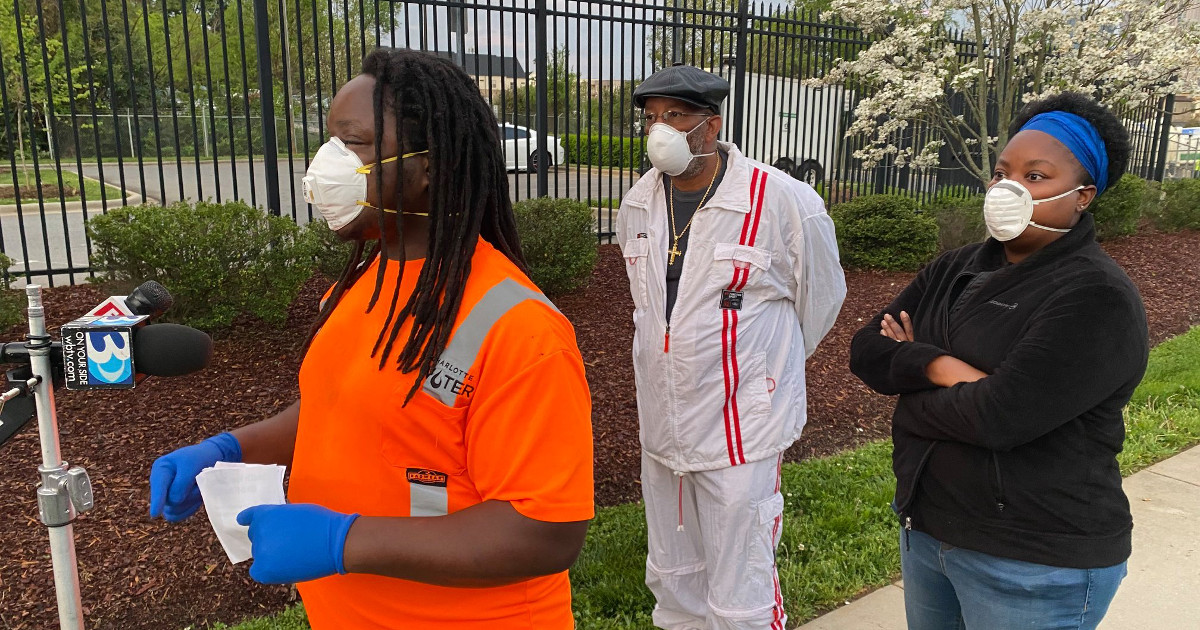 Three workers wearing masks and practicing social distancing speak at press conference