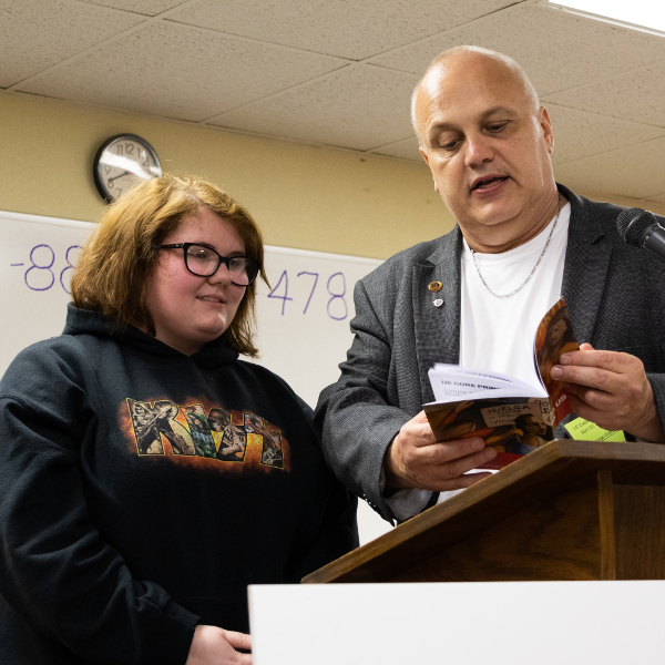 UE Eastern Region president showing a book to a young woman in a KISS sweatshirt