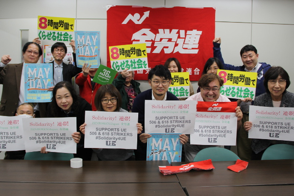 Japanese workers holding signs saying "ZENROREN/Japan supports UE 506 & 618 STRIKERS #Solidarity4UE"