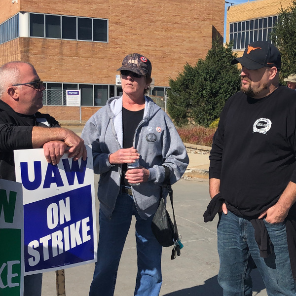 Two UE members speaking with a GM worker who holds a "UAW On Strike" sign