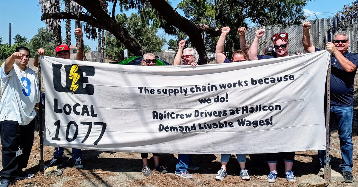 UE members with banner reading The supply chain works because we do! Railcrew drivers at Hallcon demand livable wages!