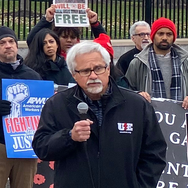 Retired UE Director of Organization Bob Kingsley speaking into a microphone at a rally