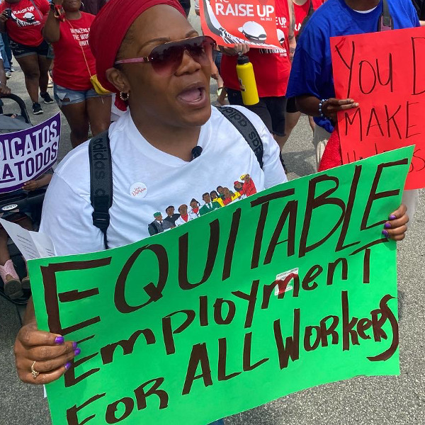 Woman with a sign reading Equitable Employment for All Workers