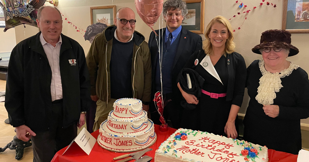 Three men and two women (one of them dressed as Mother Jones) with two Happy Birthday Mother Jones cakes