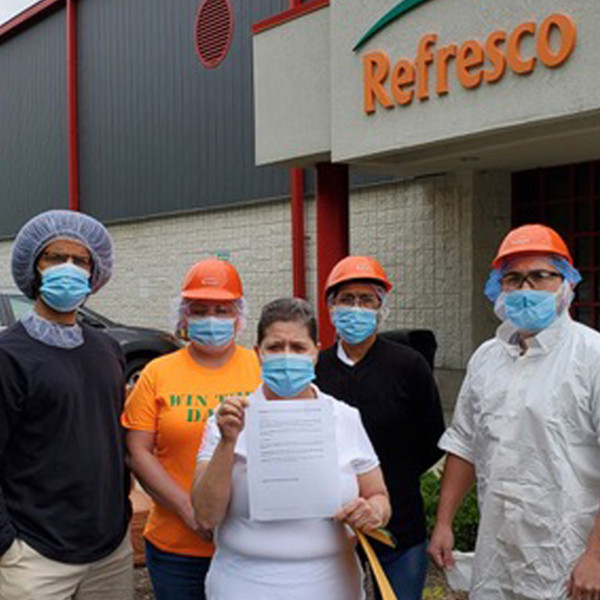 Workers outside the Refresco bottling plant holding a letter
