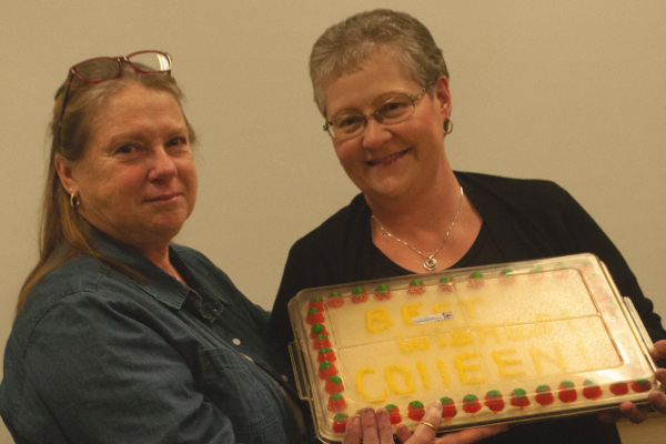 Charlene Winchell presents cake to Colleen Bochmann. Writing on cake reads "Best wishes Colleen!"