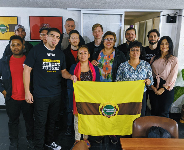 A dozen men and women standing behind the flag of the Fensuagro union